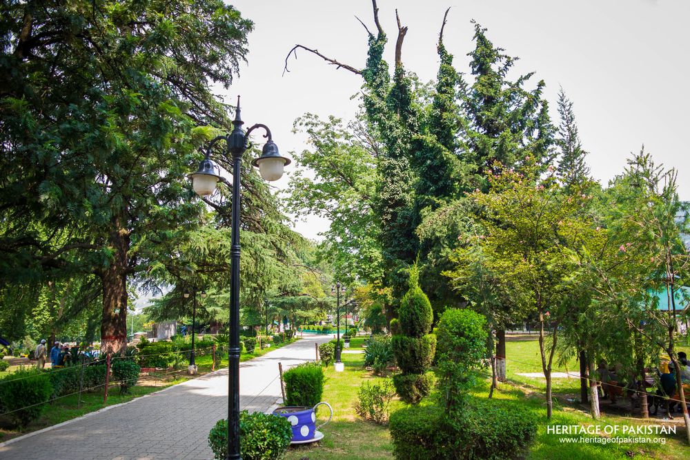 A peaceful walkway lined with shaped greenery welcomes visitors to Lady Garden